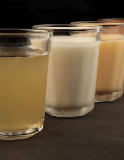 Four glasses of batidas with different flavors and colors, arranged in a row.