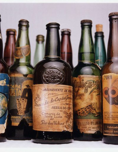 Collection of antique cachaça bottles. The bottles are arranged side by side, creating a visual that evokes the history and tradition of cachaça production in Brazil.