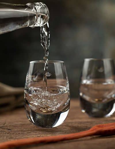 Crystal cachaça glass with a crown logo from Vista Alegre, being filled as part of a design collaboration with Academia da Cachaça.